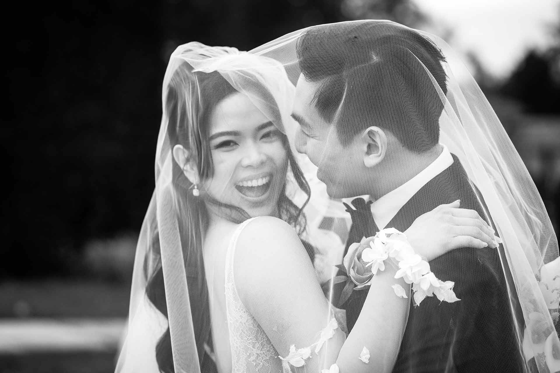 bride and groom laughing under a veil at their Hedsor House wedding